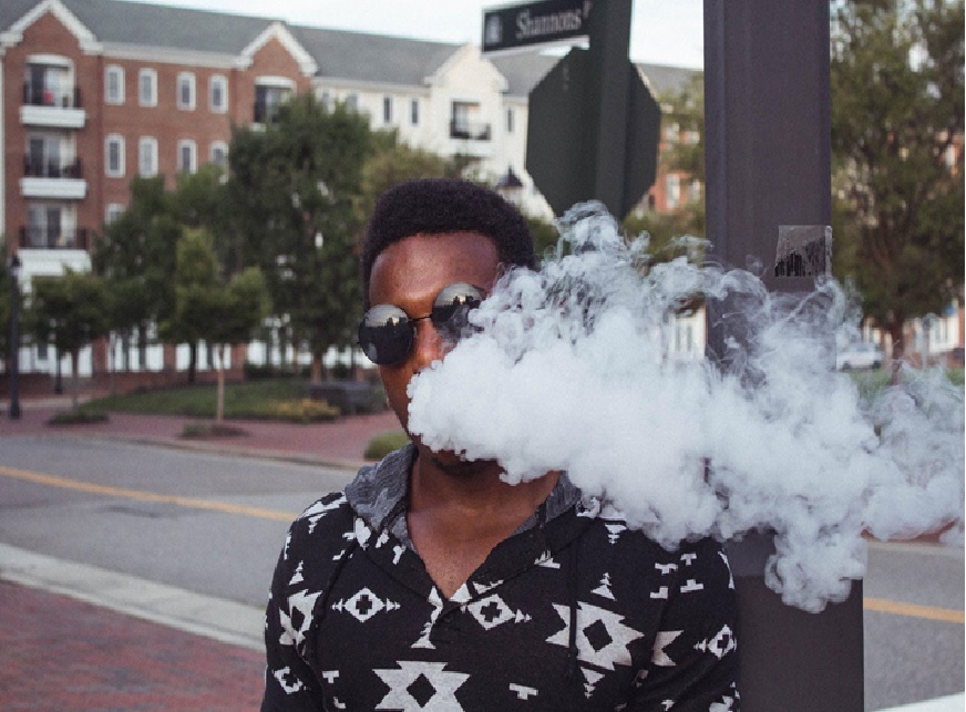 A man obscured behind his cloud of vape smoke.